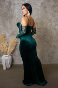 Woman in a green evening gown with sheer gloves against a textured wall.