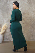 Woman wearing a green dress standing against a textured wall.