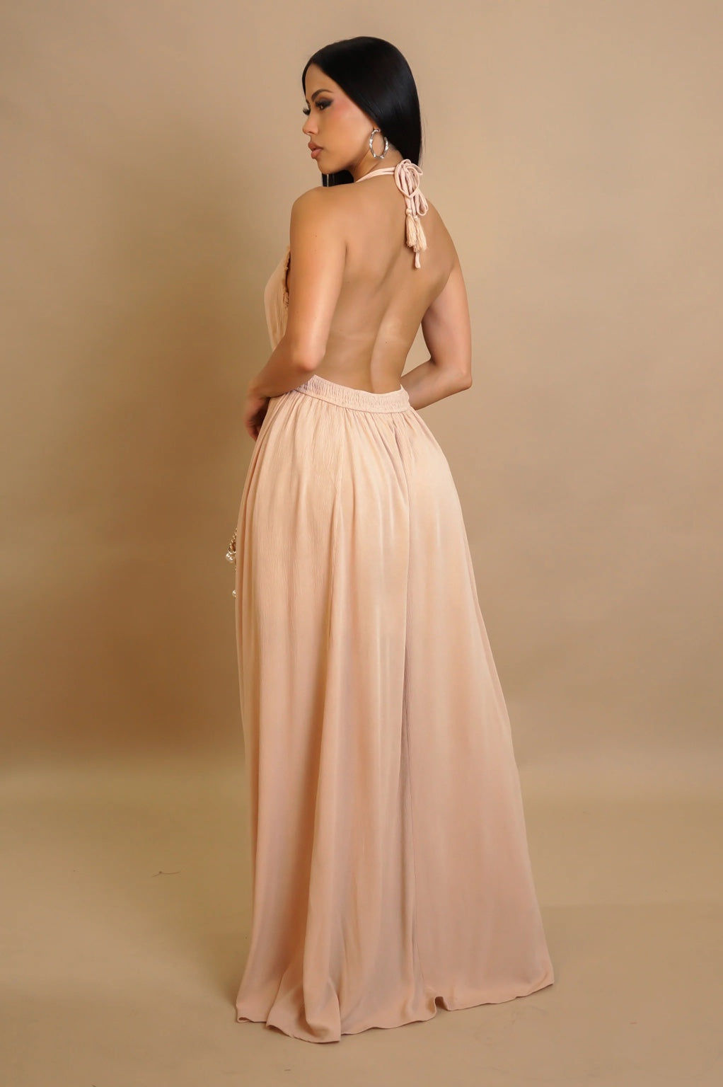 Woman wearing a long, flowing dress with a beige background