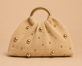 Beige handbag with gold studs and handle on a beige background