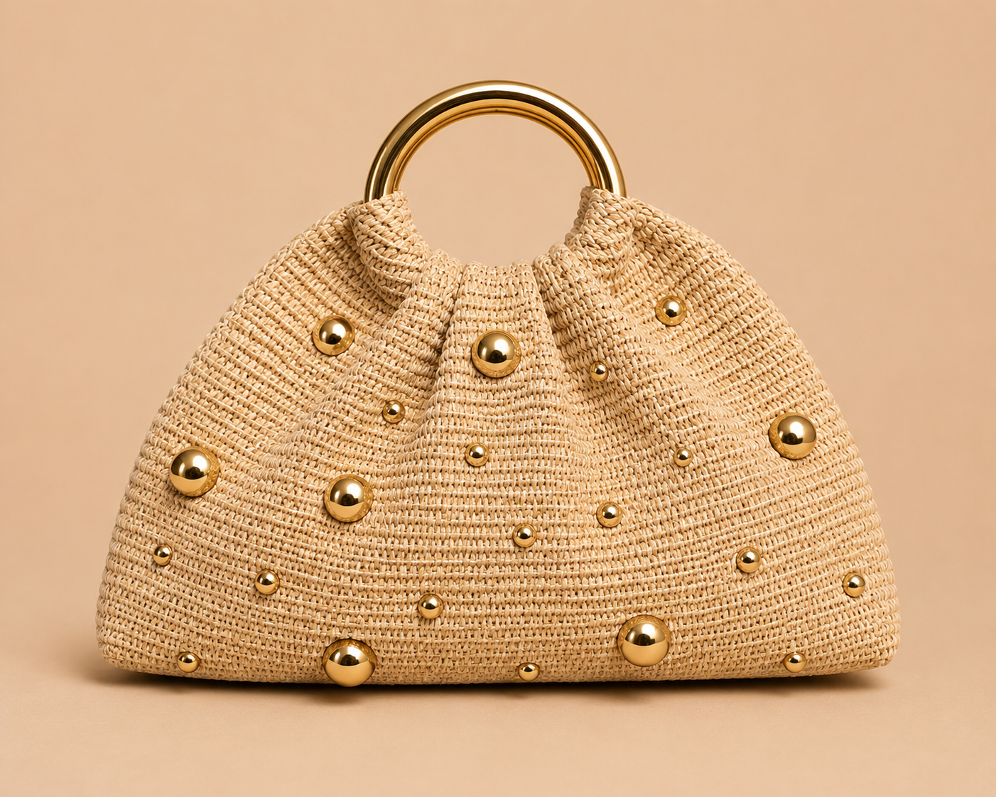 Beige handbag with gold studs and handle on a beige background