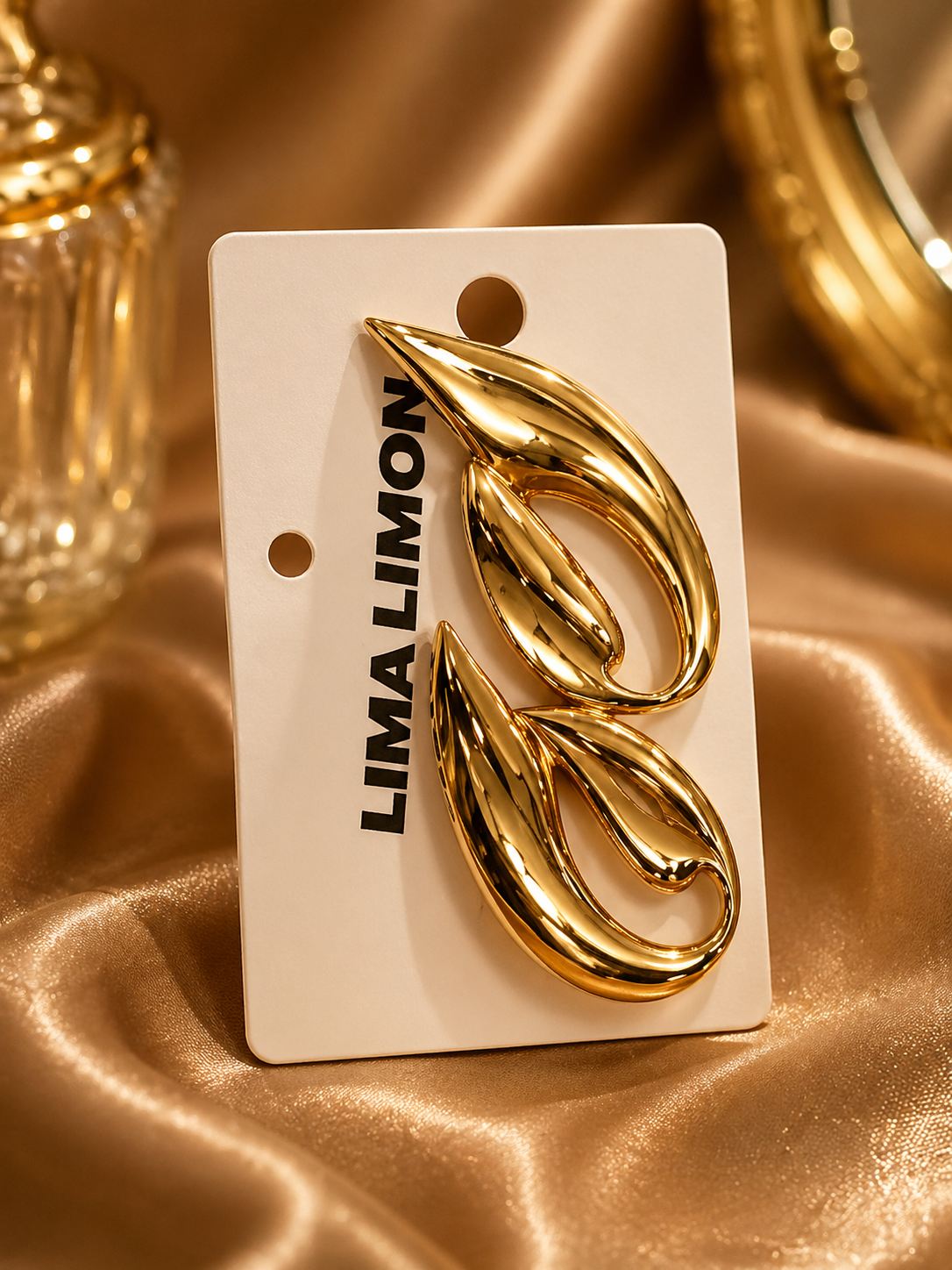 Gold earrings on a Lima Limon branded card against a gold fabric background