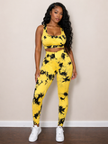 Woman wearing a yellow and black tie-dye outfit against a beige wall.