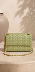 Green quilted handbag with gold chain on a beige surface