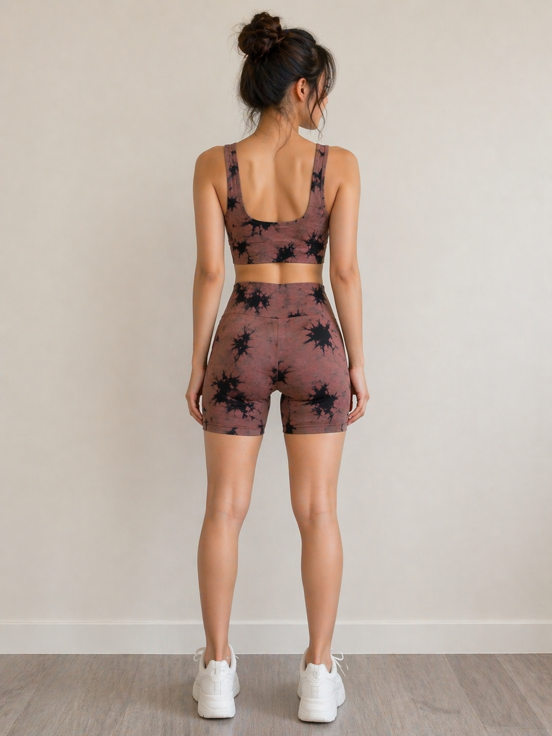 Woman wearing a patterned sports bra and shorts set on a plain background