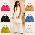 Woman in a white outfit holding a white handbag with colorful handbags displayed around her.