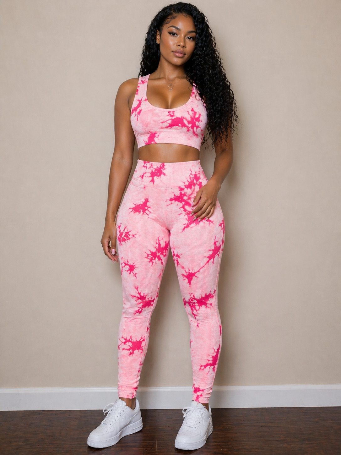 Woman wearing a pink tie-dye athletic outfit against a beige wall.