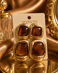 Gold and amber square earrings on a 'andante' branded card against a gold background.
