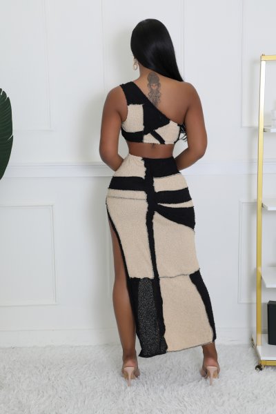 Woman wearing a black and beige geometric dress with a white wall background
