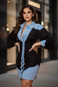 A woman models a color-block mini shirt dress with a black body and light blue denim-like panels on the shoulders, collar, placket, and hem, set against a blurred storefront background.