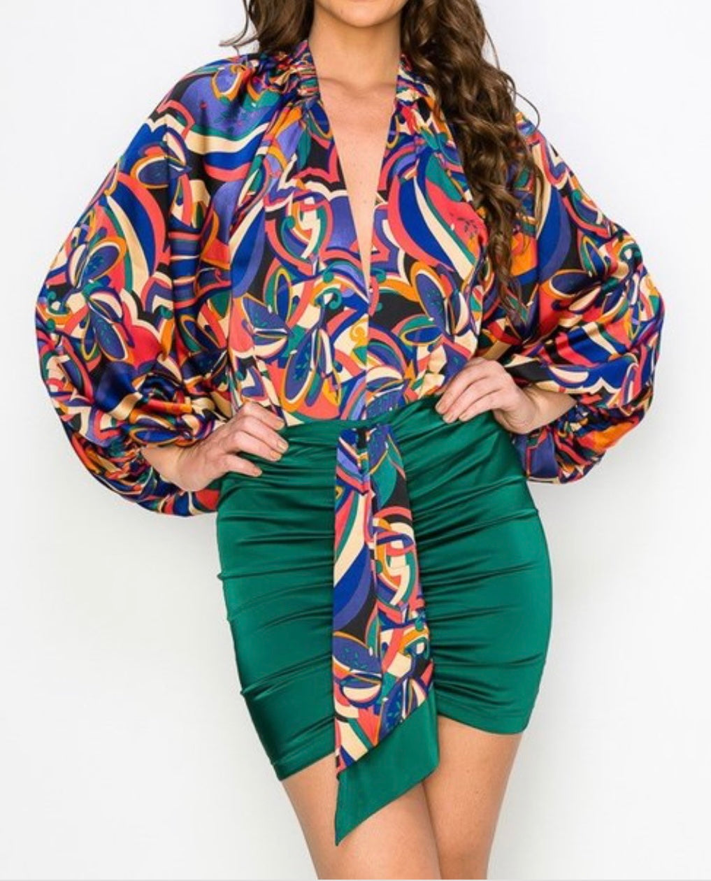 Woman wearing a colorful patterned top and green skirt on a white background