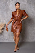Woman in a brown leather outfit posing against a gray background
