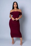Woman wearing a burgundy off-shoulder dress against a gray background